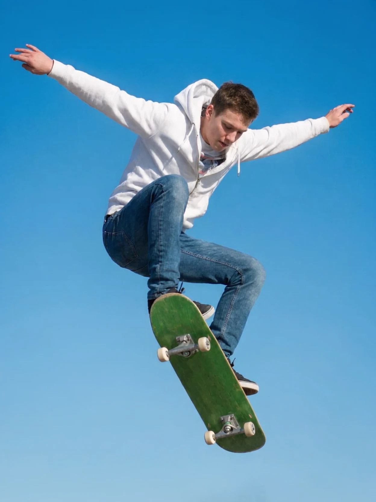 Start frame: Jeff mid-air against a clear blue sky, the green board flipped under his feet, arms out for balance